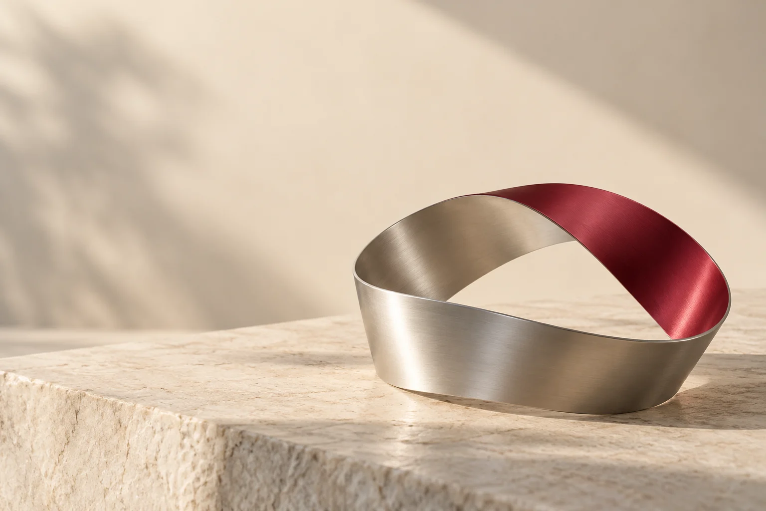 A continuous aluminum loop with a burgundy segment on pale stone.