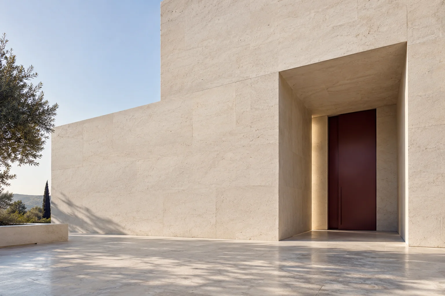 A burgundy door set within a sunlit limestone facade.