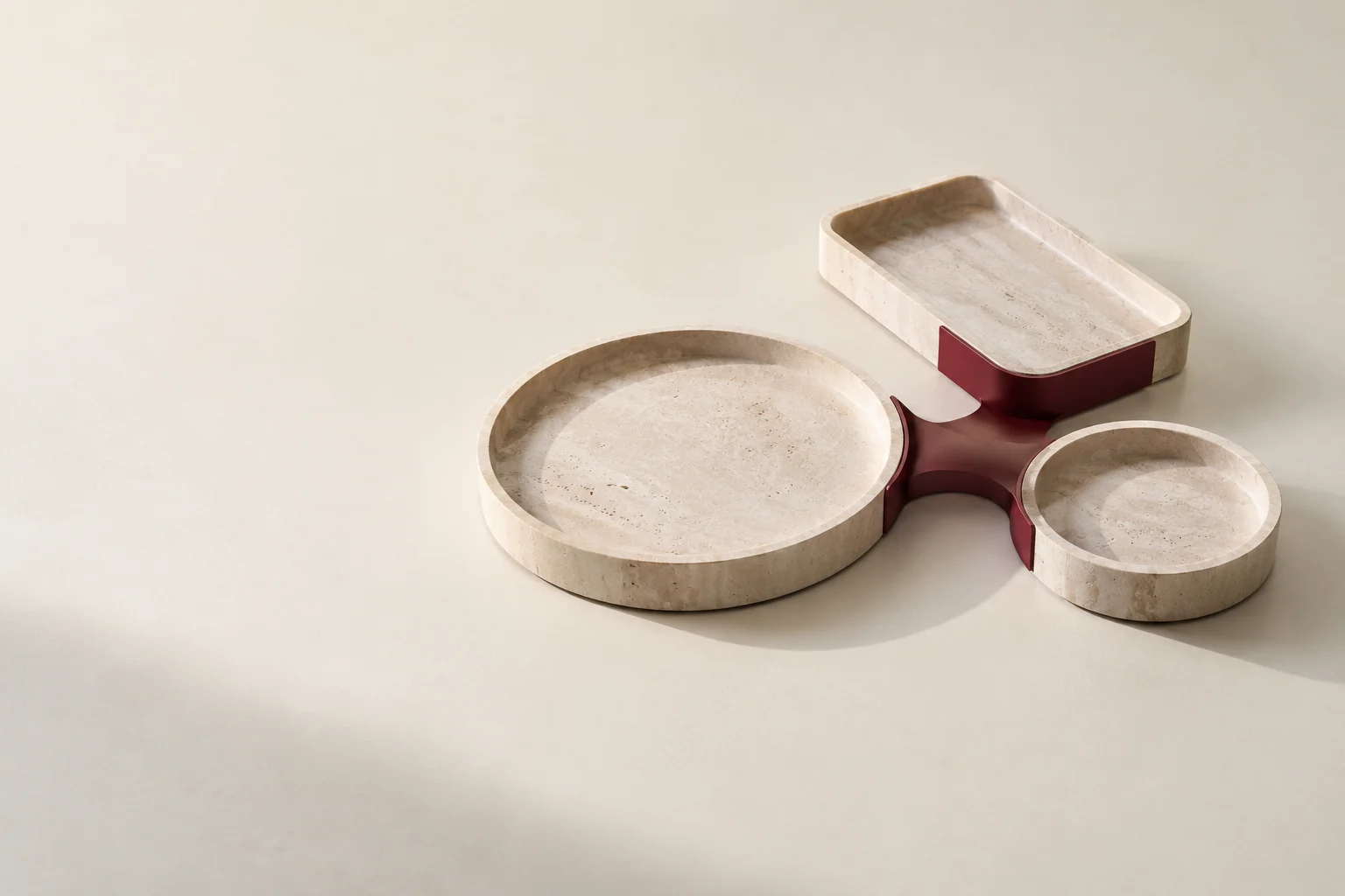 Three stone trays joined by a burgundy channel, illustrating connected finance responsibilities.