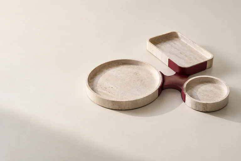 Three stone trays joined by a burgundy channel, illustrating connected finance responsibilities.