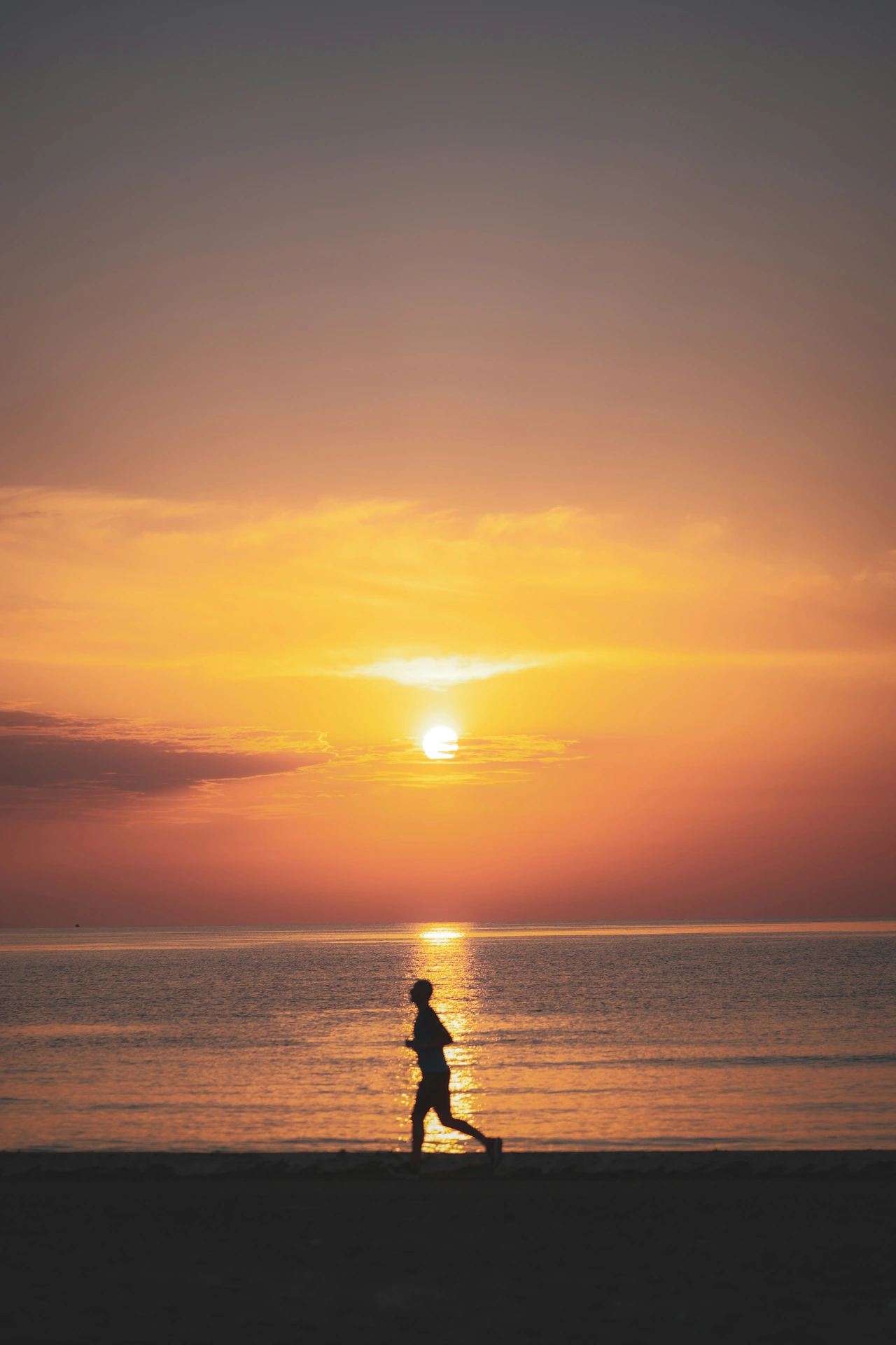 A runner silhouetted against golden light on Valencia’s Mediterranean shoreline