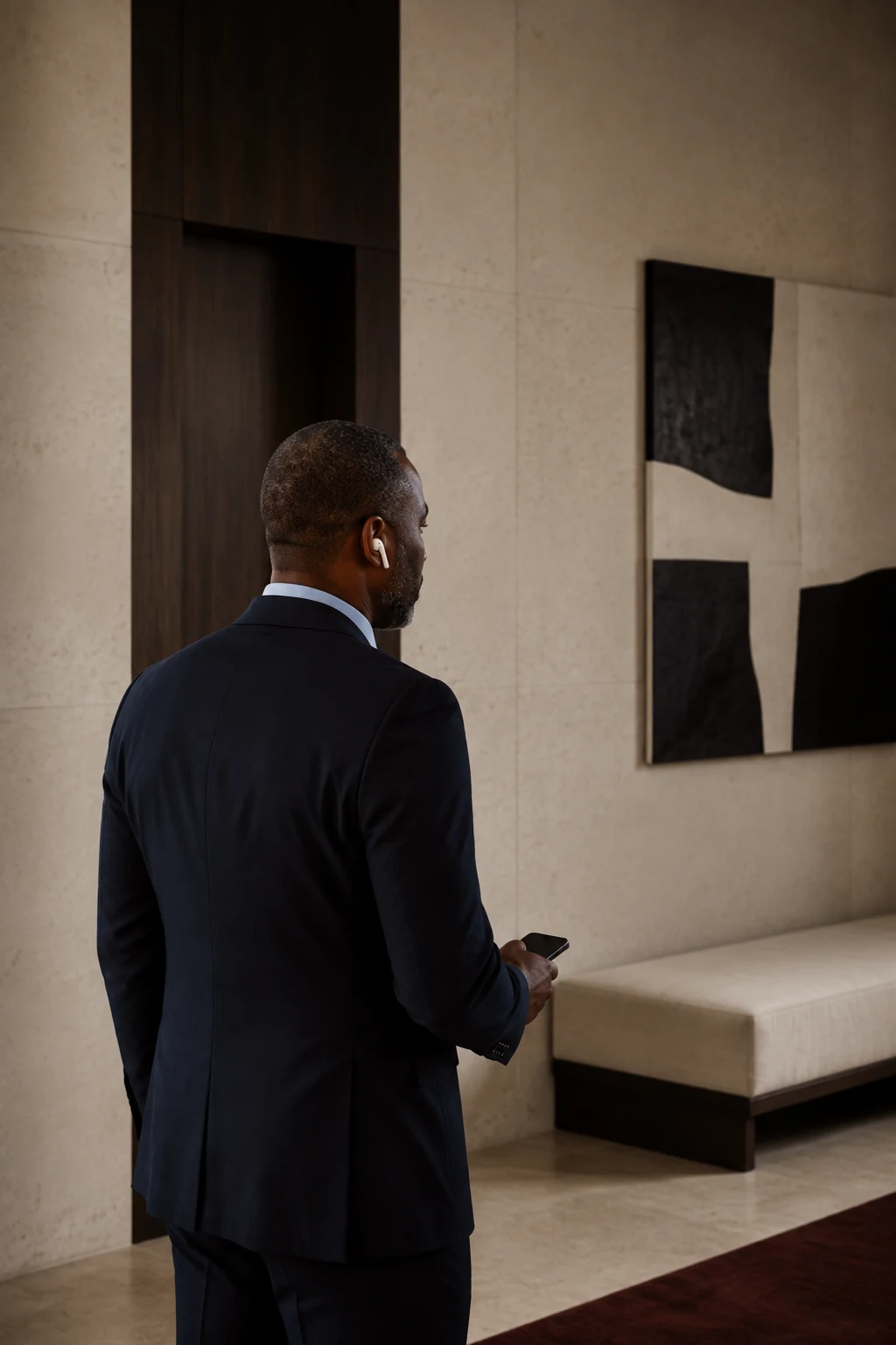 Senior executive standing in a quiet architectural interior.